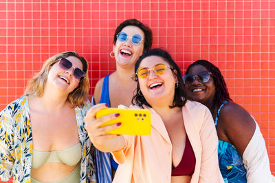 Portrait of smiling friends standing against wall