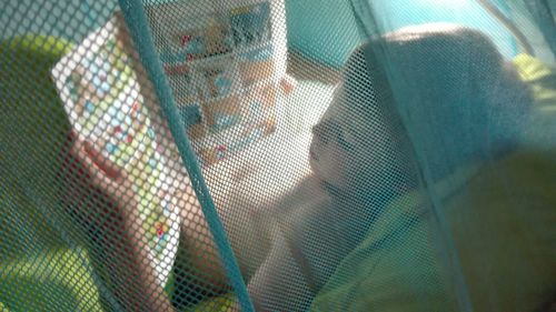 High angle view of boy reading book while lying on bed at home