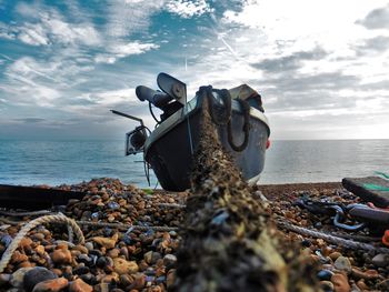 Boat moored on shore with rope against sky