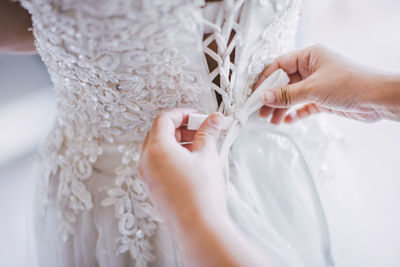 Close-up of hand helping bride wearing wedding dress