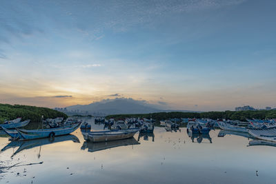 Boats moored in lake against sky during sunset