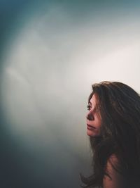 Thoughtful mature woman looking away against wall