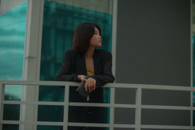 Woman looking away while standing against window