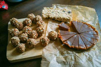 High angle view of almond balls and chocolate tart with nut bar on cutting board