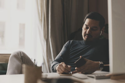 Businessman preparing notes while sitting at desk in office