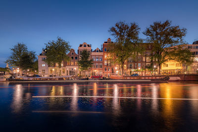 Buildings by river against clear sky