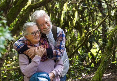 Smiling couple embracing while sitting at forest