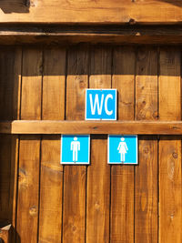 Close-up of restroom signs on wooden door