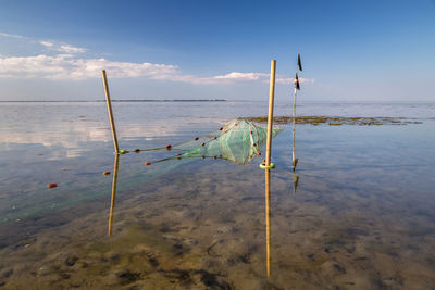 Wooden posts on beach against sky