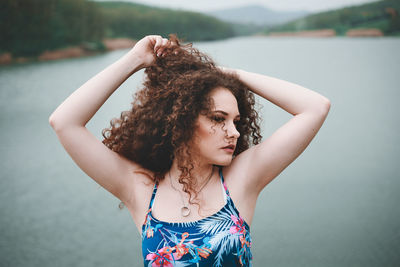 Beautiful young woman with arms raised standing in water