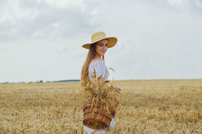 Ripe wheat ears in wicker basket in woman hands walking in wheat field. harvest concept