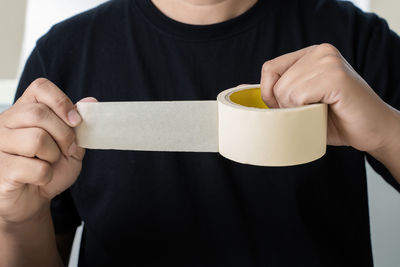 Midsection of man holding duct tape