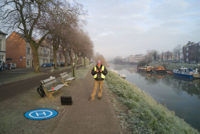 Man on canal in city against sky