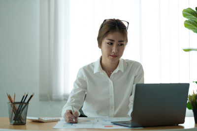 Young woman using mobile phone while sitting on table