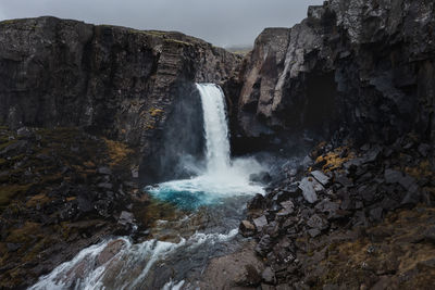 High-angle view of folaldafoss waterfall, southern iceland, turquoise pool in volcanic landscape