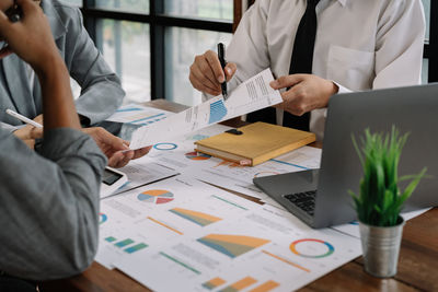 Midsection of business colleagues working on table