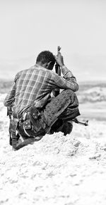 Rear view of man photographing on beach