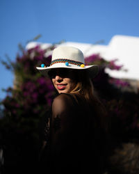 Portrait of young woman wearing hat against sky