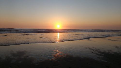 Scenic view of beach against clear sky during sunset