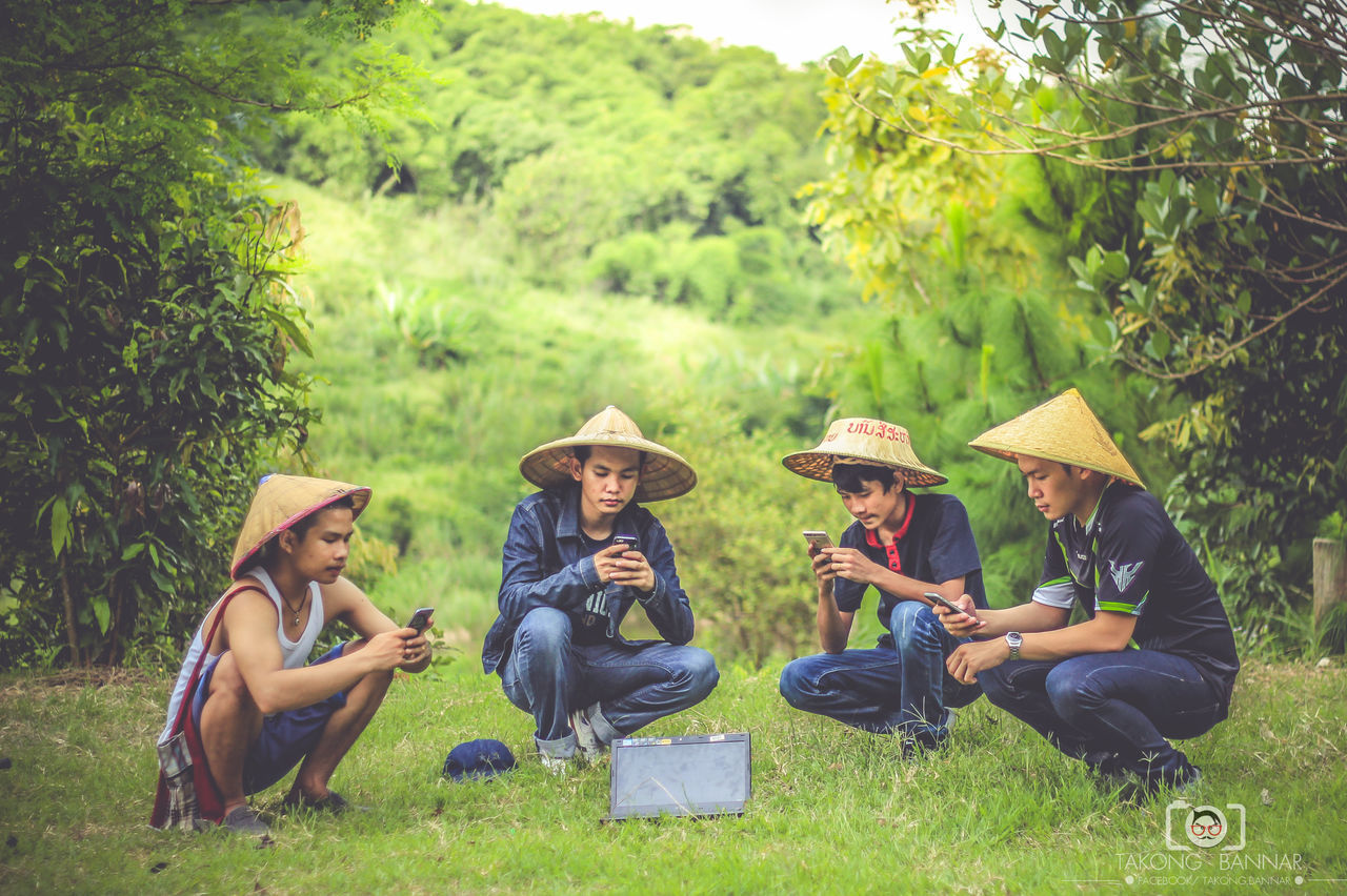 grass, togetherness, leisure activity, tree, lifestyles, casual clothing, sitting, friendship, full length, young adult, field, green color, enjoyment, person, day, weekend activities, performance, outdoors, focus on foreground, grassy