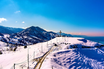 Scenic view of snow covered mountains against blue sky