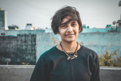 Portrait of smiling young woman standing against sky