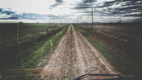 Road amidst agricultural field against sky