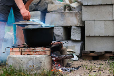 Man cooking fish soup in the iron bowler over a campfire. fish soup boils in cauldron. soup in a pot 