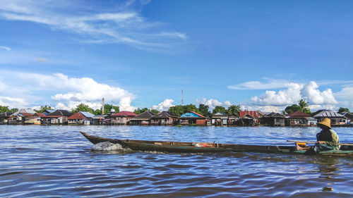 Man sitting on boat in river against sky