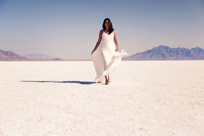 Full length of woman standing on desert against clear sky