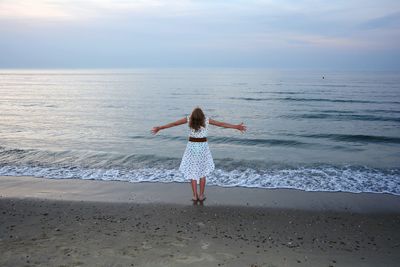 Rear view of boy on beach against sky