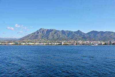 Scenic view of sea by buildings against blue sky