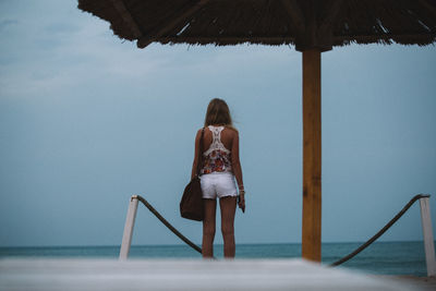 Rear view of young woman standing at beach
