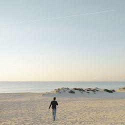 Man standing on beach against clear sky