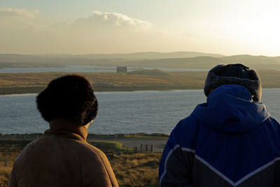 Rear view of people looking at view against sky