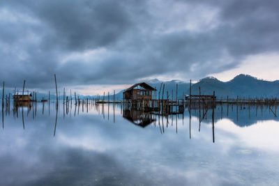 Panoramic view of wooden posts in lake against cloudy sky