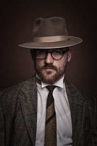 Portrait of man wearing hat against black background