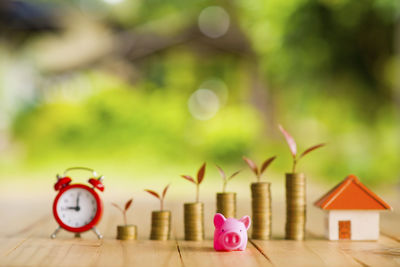 Stacked coins with piggy bank and alarm clock on table