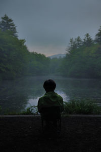 Rear view of man sitting by lake