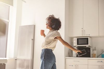 Side view of young woman standing at home