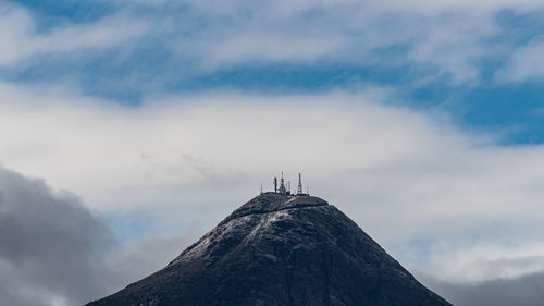 Low angle view of cross on mountain against sky