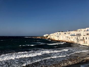 Scenic view of beach by buildings against clear sky