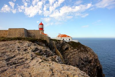 Lighthouse by sea against sky