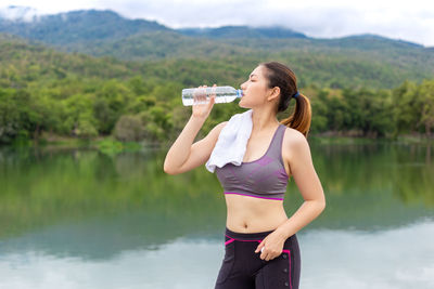 Full length of a woman drinking water at lake