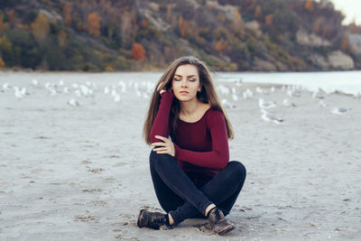 Young woman with eyes closed sitting at beach