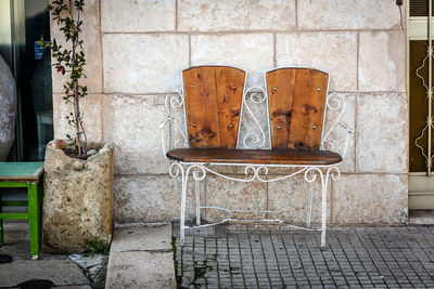 Empty chair on footpath against wall of old building