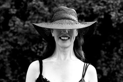 Smiling woman wearing hat against trees