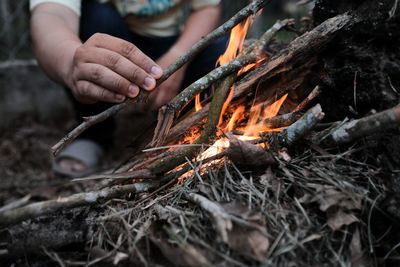 Close up view of a hand lighting up a fire while camping in the forest