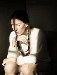 Woman sitting on a chair with white wool sweater in thoughtful attitude ii