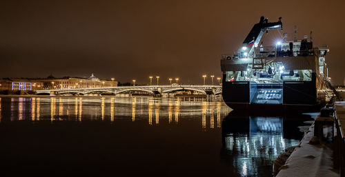 Illuminated bridge over river against sky at night